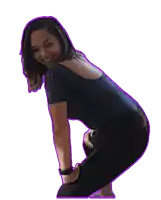 a woman in a blue shirt and black pants is squatting down and smiling
