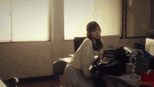 a woman sits at a desk in front of a window with a sticker on the wall that says ' samsung ' on it
