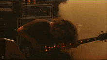 a man playing a bass guitar with a smokey background