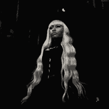 a black and white photo of a woman with long blonde hair in a dark room .