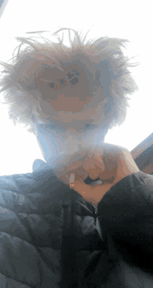 a person with messy hair smoking a cigarette in front of a window