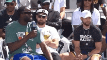 a group of men are sitting in a stadium watching a game .