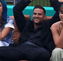 a man is sitting on a couch with his arms up and smiling