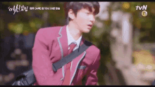 a young man in a school uniform is walking down the street .