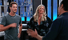 a man and a woman are standing in front of a bar with bottles of gin