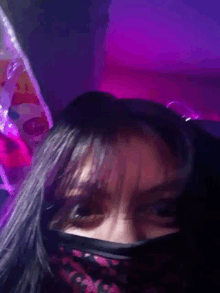 a close up of a woman wearing a mask in front of a purple background .
