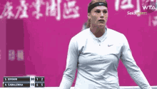 a woman wearing a headband is standing in front of a scoreboard that says 30 1 2