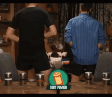 two men are dancing in front of a table with a bottle of body powder on it