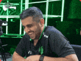a man wearing a black shirt that says 929 on it smiles in front of a green background