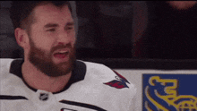 a hockey player with a beard wearing a white jersey with a red eagle on the front