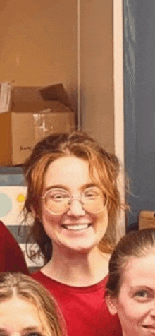 a woman wearing glasses is smiling for the camera while standing next to another woman .