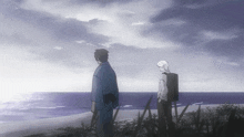 two people standing on a beach looking at the water