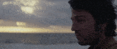 a close up of a man 's face with a cloudy sky behind him