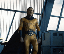 a man in a yellow superhero costume is standing in front of a window with kepler written on the bottom right