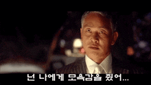 a man in a suit and tie is standing in front of a car .