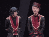 a group of people standing on a stage with one wearing a red top hat