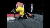 two wrestlers in a ring with a sign that says honor on it