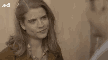 a man and a woman are looking at each other and the woman is wearing a brown jacket
