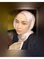 a woman wearing a pink hijab and a black jacket looks at the camera