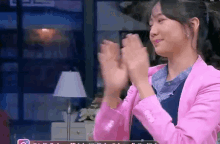 a woman in a pink jacket is clapping her hands in a room