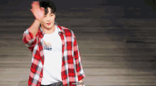 a young man wearing a plaid shirt and a white t-shirt is standing on a stage .
