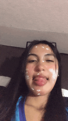 a girl with white spots on her face sticks her tongue out
