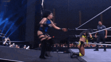 two women are wrestling in a ring and one is wearing a blue top