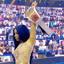 a woman in a gold dress holds up a gsdf championship belt