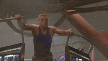 a man in a blue tank top is sitting on a machine