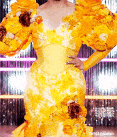 a woman is wearing a yellow dress with flowers on the sleeves