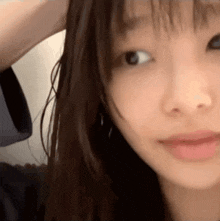 a close up of a woman 's face with a hand in her hair .