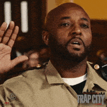 a man in a tan uniform with trap city written on the bottom right