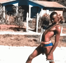 a woman in a bikini is standing on a sidewalk in front of a house .