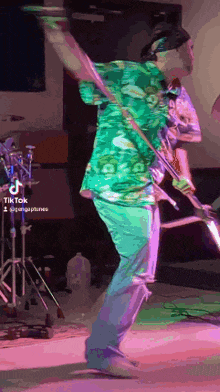 a man in a green shirt playing a guitar on stage