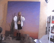 a woman is standing in front of a blue wall in a room holding a hoodie .