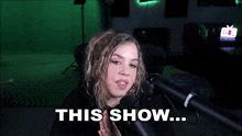 a woman sitting in front of a microphone with the words " this show " written below her
