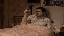 a man is sitting in a bed holding a gun .