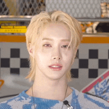 a young man with blonde hair and red eyes is wearing a blue and white sweater .