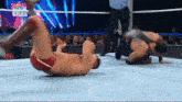 two men are wrestling in a wrestling ring with a referee in the background .