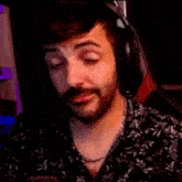 a man with a beard is wearing headphones and making a funny face while sitting in a chair .