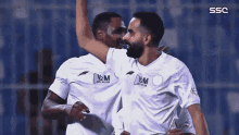 two soccer players are celebrating a goal with ssc written on the bottom