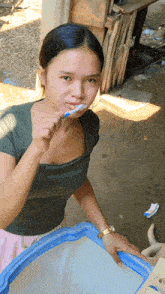 a woman brushing her teeth with a toothbrush
