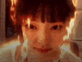 a close up of a woman 's face with flames coming out of her head .