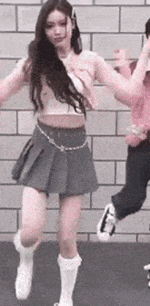 a woman in a gray skirt is dancing next to a man in a pink jacket .