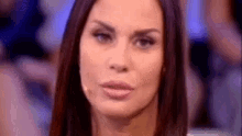 a woman is making a funny face while sitting in front of a crowd .