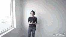 a woman is standing in front of a window with her hands folded in front of her face .