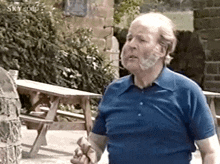 an elderly man with a beard is standing in front of a picnic table .