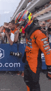 a man wearing a helmet stands in front of a sign that says p.com