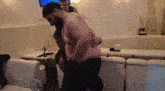 a shirtless man is carrying another shirtless man in a room