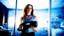 a woman is holding a gun in a room with a window .
